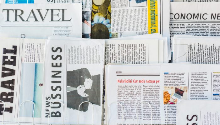 different print business and travel newspapers on stand